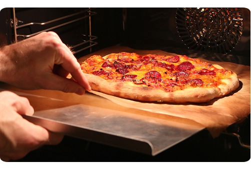 Kombispaden benyttes til at tage en pizza ud af ovnen